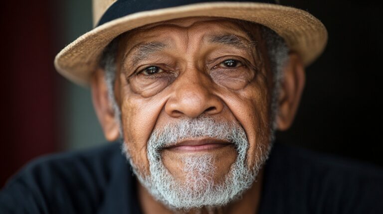 Close-up portrait of an elderly man wearing a straw hat, showcasing a gentle expression with a well-groomed white beard