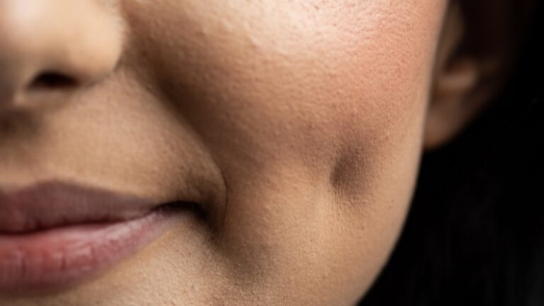 A close-up of a person smiling, showing a natural dimple on their cheek, illustrating the concept of "how to get dimples"